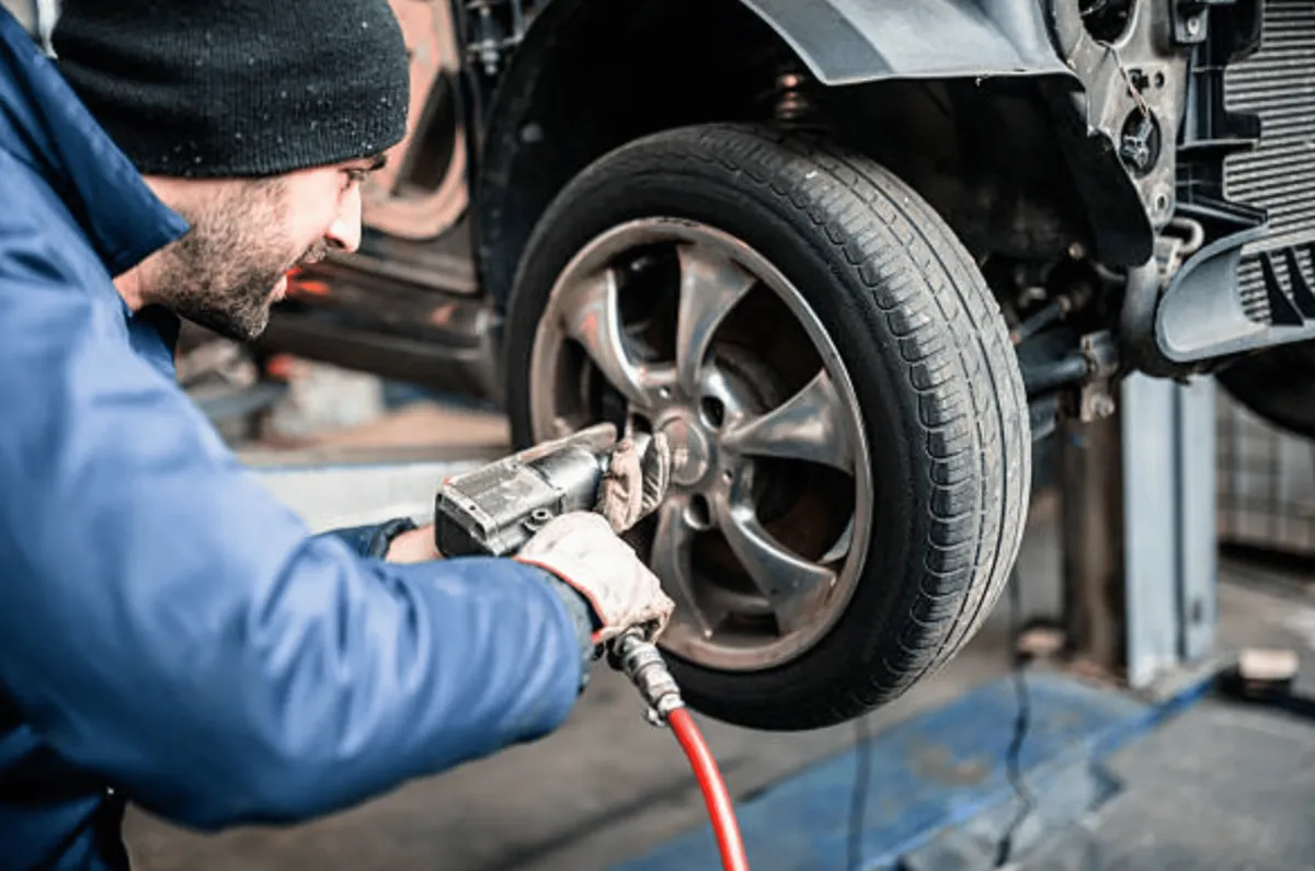Mechaniker montiert ein Fahrzeugrad auf der Hebebühne